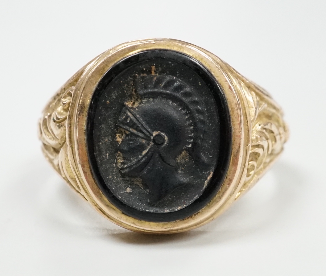 A 1970's 9ct gold and black onyx? set signet ring, carved with the bust of a Roman soldier, size T, gross weight 8 grams.